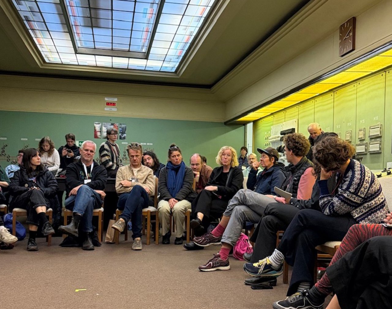 Eine Gruppe von Menschen sitzt bei einer Veranstaltung des OSTEN Festivals in einem Raum zusammen.