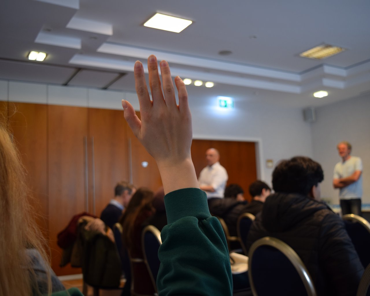 Eine Schülerin hebt die Hand, um eine Frage zu stellen.